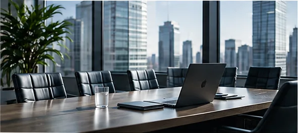 Boardroom table with leather chairs and a laptop in front of city skyline windows