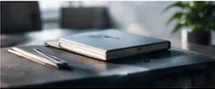Closed notebook and pen on a dark desk