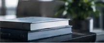 Stack of books on a desk with a small plant